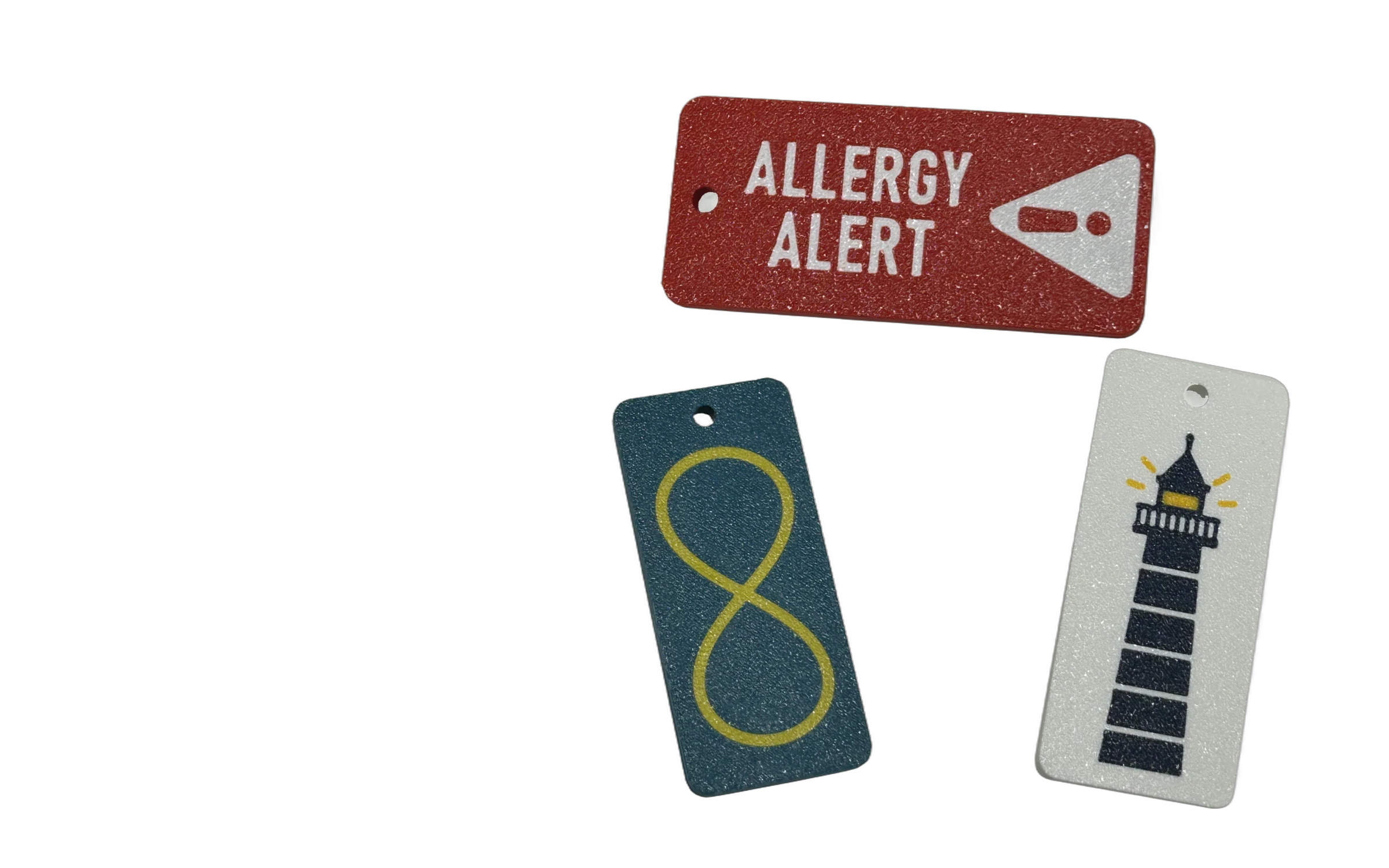 Original South Pier Co tags: red Allergy Alert, blue with gold infinity, and white with navy and gold lighthouse.